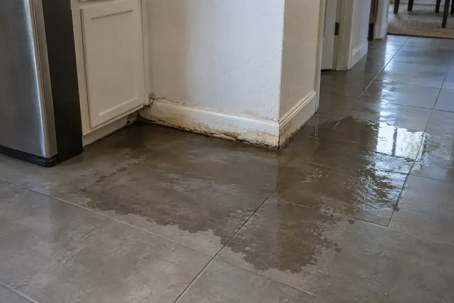 Water spreading across a tile floor from a hidden leak in a Modesto kitchen