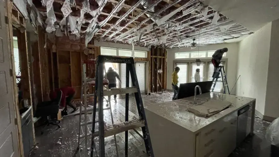 Restoration crew removing wet ceiling and drywall during a water damage job in Modesto