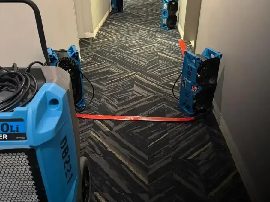 Dehumidifier and air movers lining a commercial hallway during a Modesto dry-out